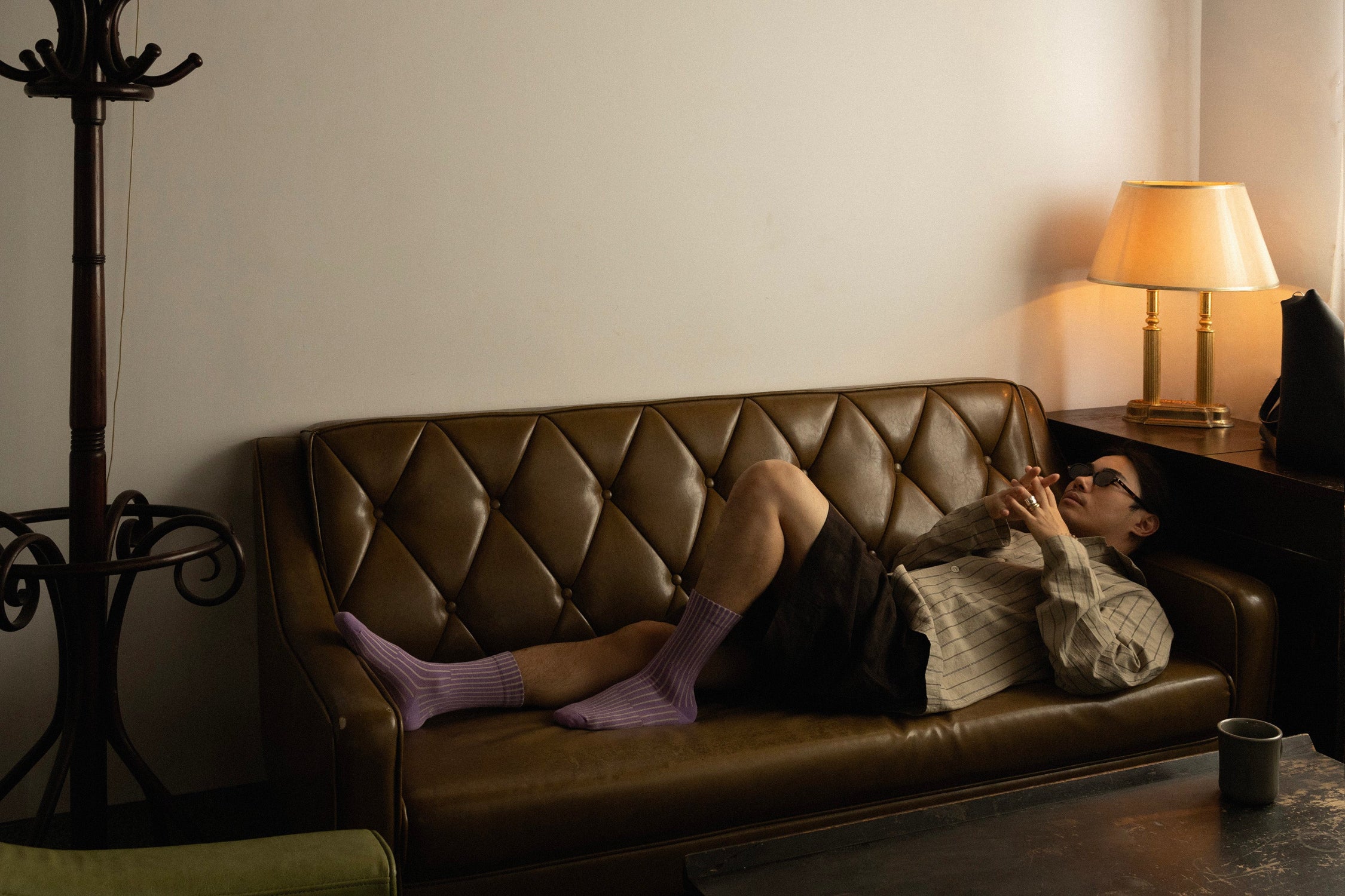 Person lying on a brown leather couch in Salio's Split socks in a beautiful room.