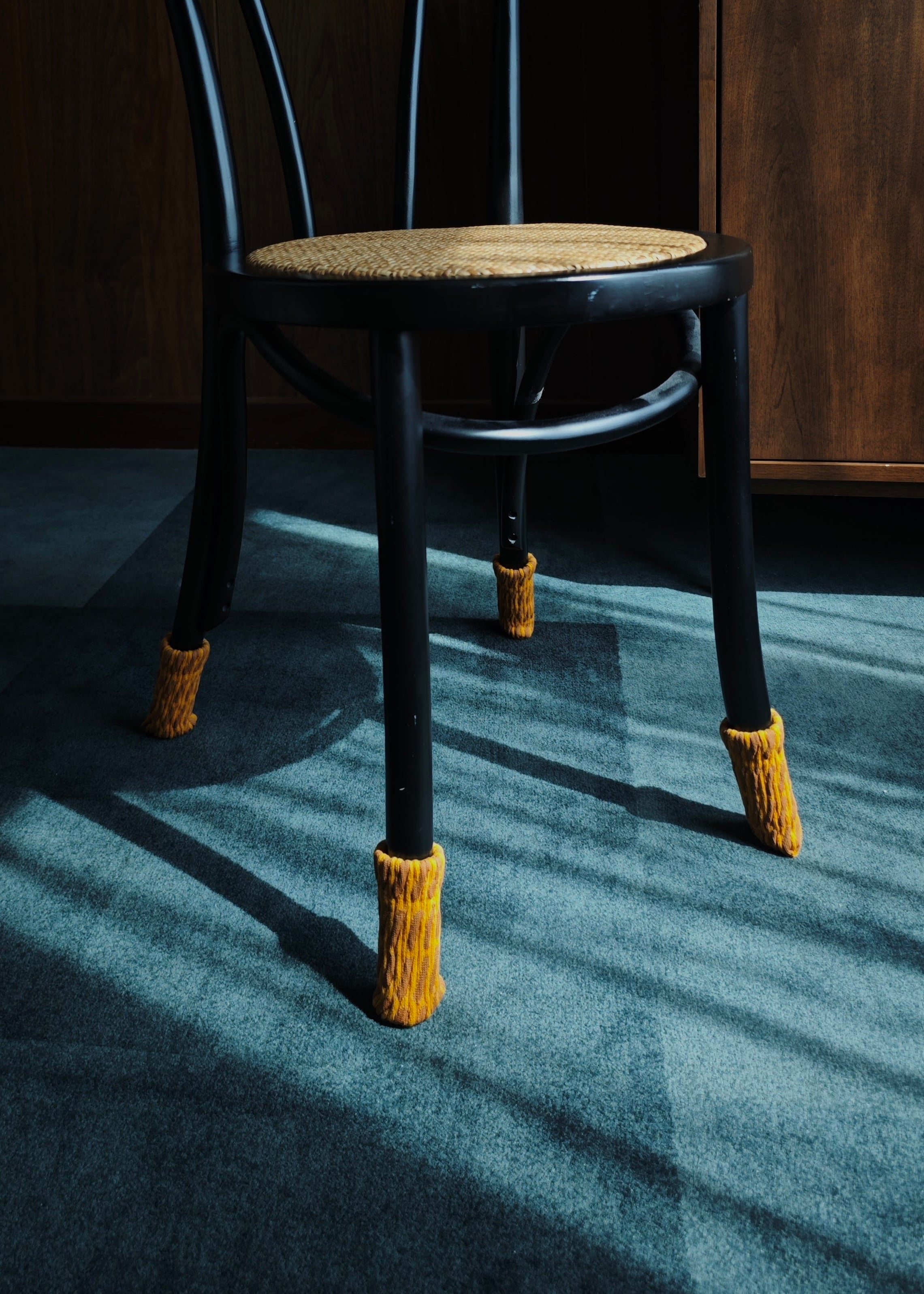 Black chair with knitted footrests on a dark floor