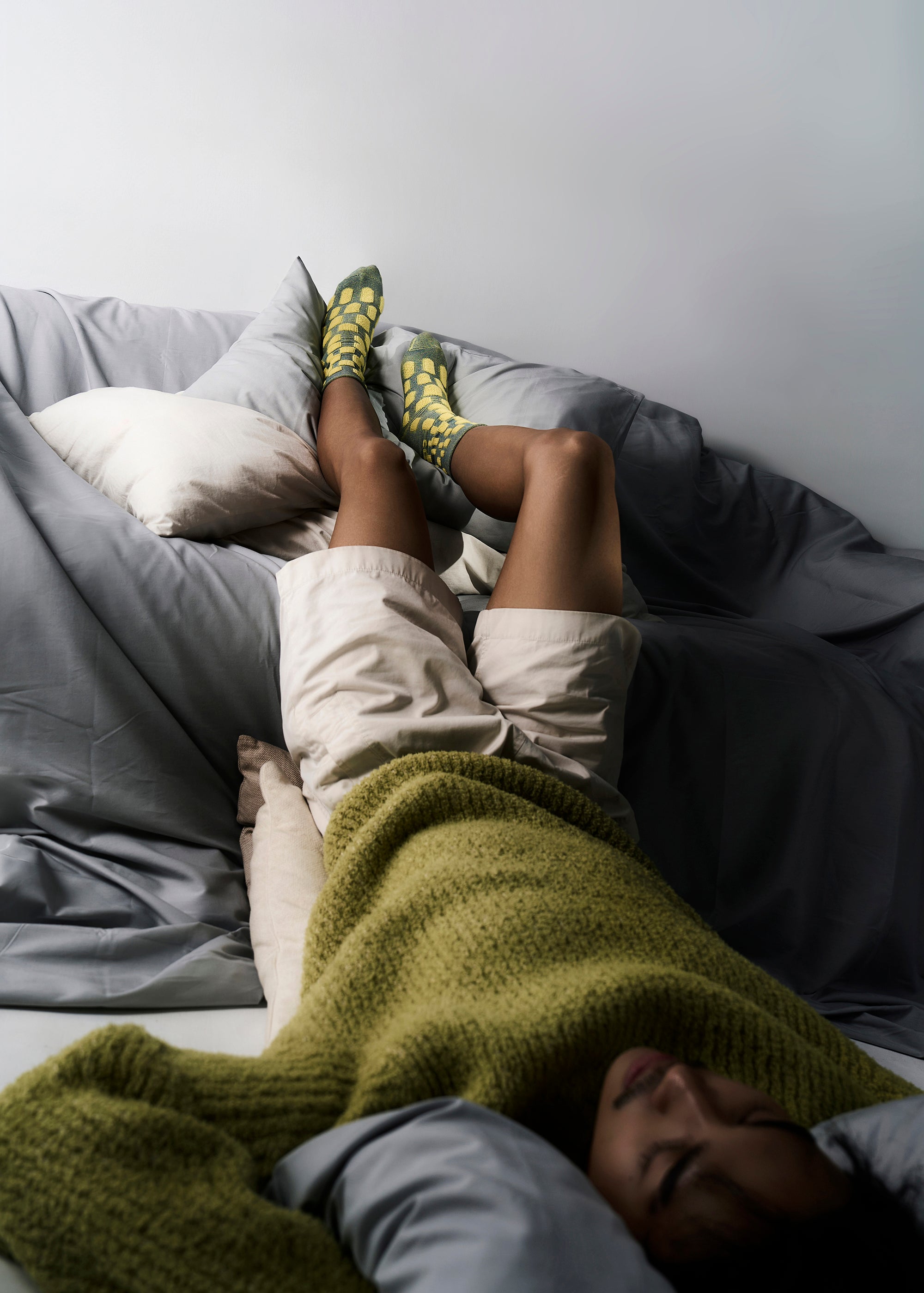 A Model Lying upside down on a couch wearing The Cube Cotton Terry Socks in Color Glowing Ocean