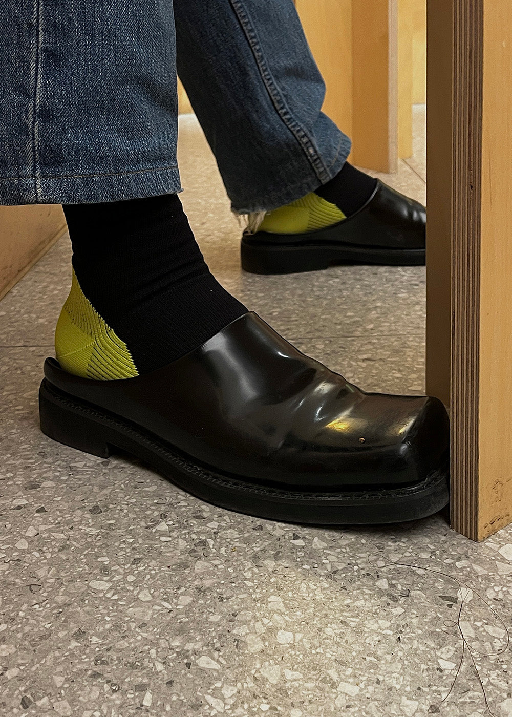 Close of up a person wearing a Black leather slipper with the Guard Compression socks in Black and Lime