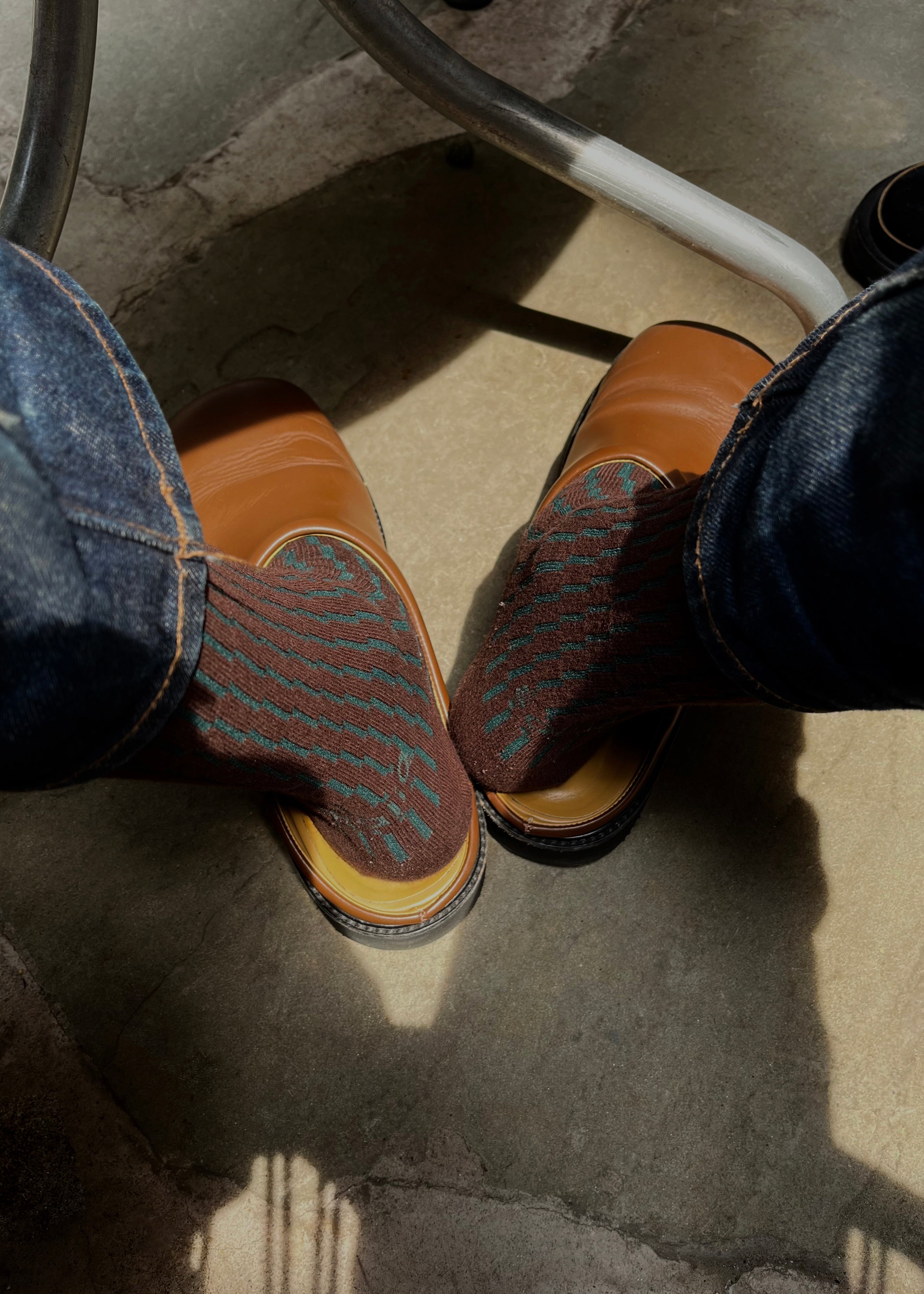 Close up of a person wearing a slipper with the Shifting Grid Rib Socks in Color Forest and Chocolate