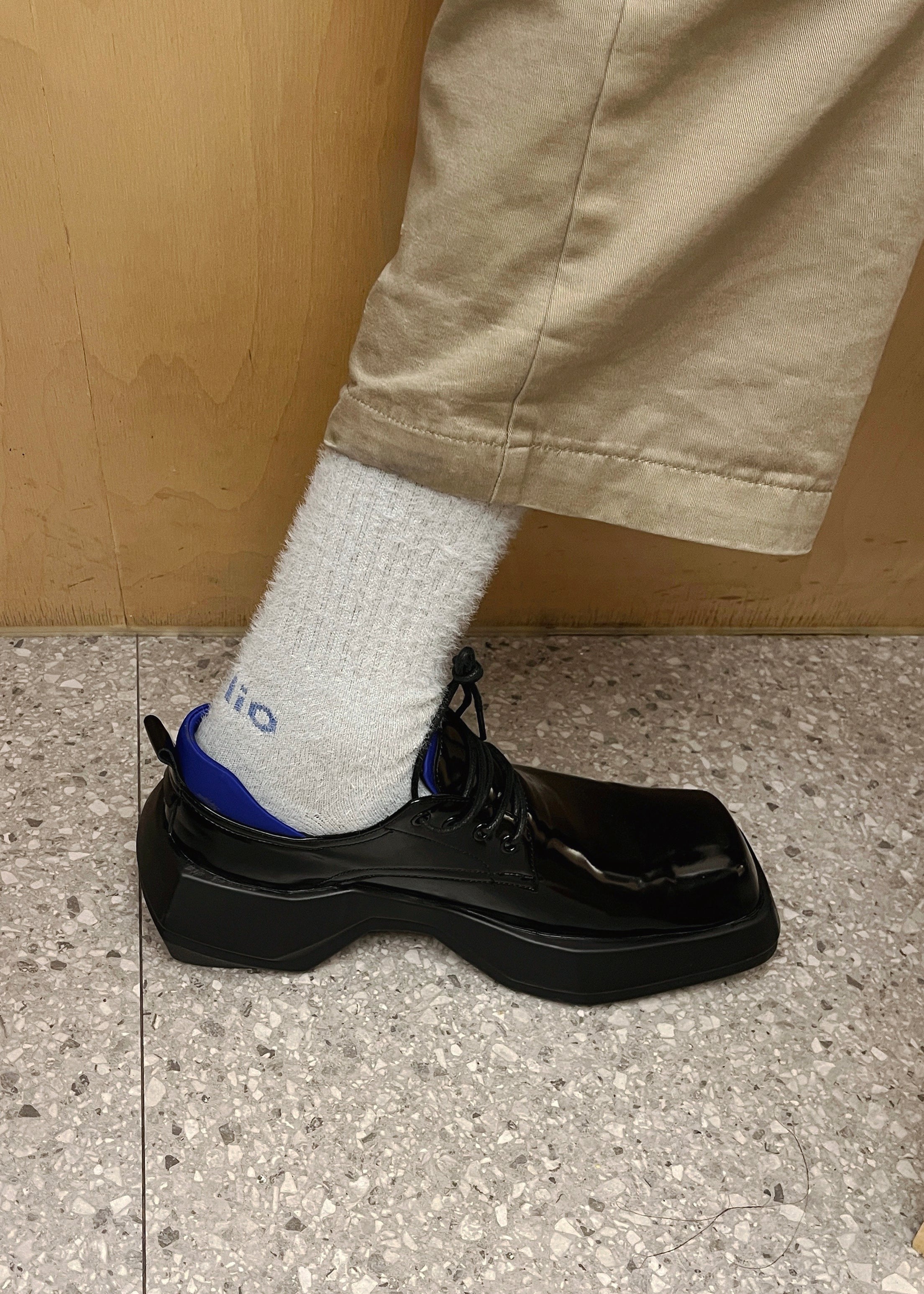 Close up of a person wearing black leather loafer with the Troll Mohair Socks in Pale Grey