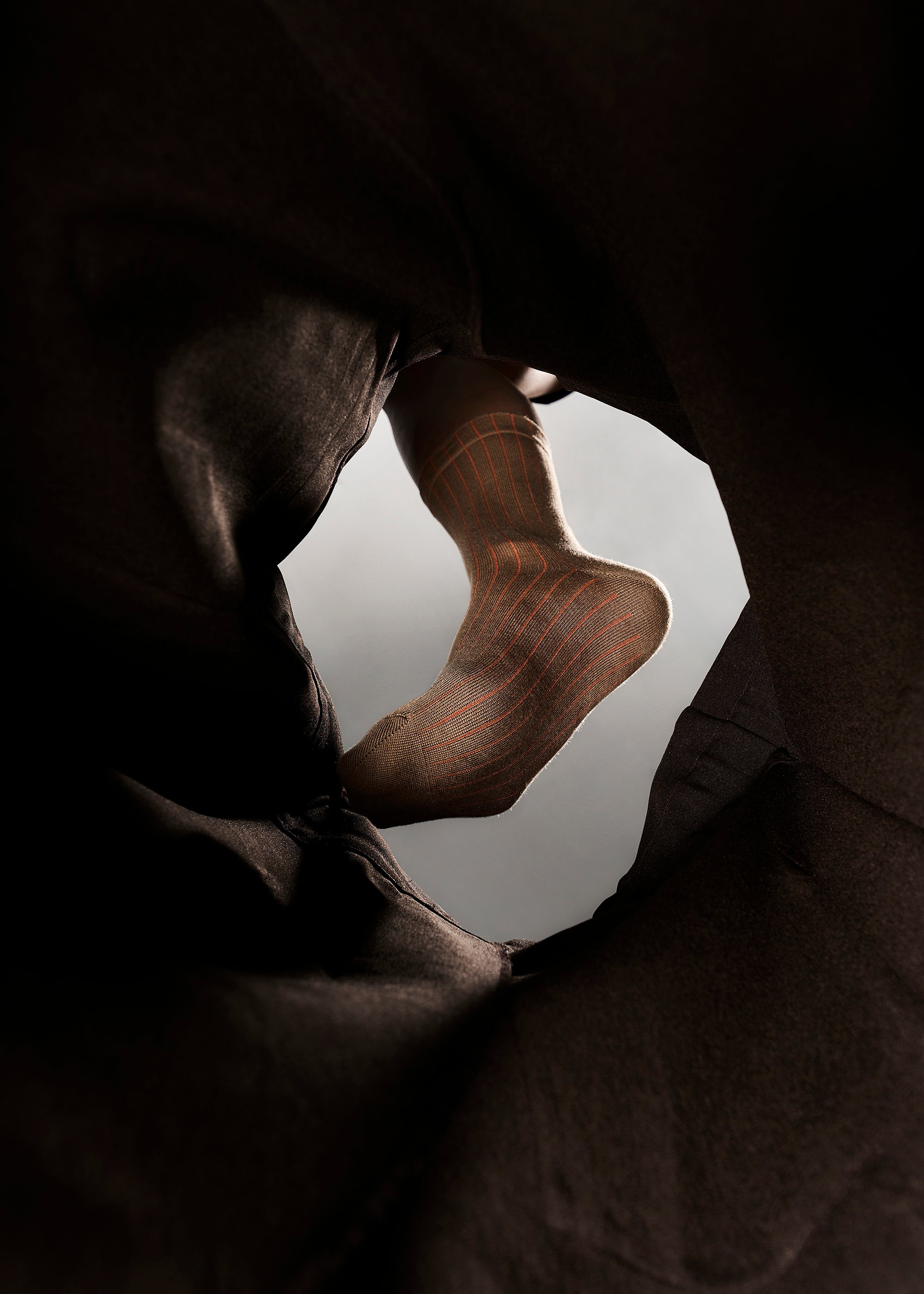A tunnel view Close-up of a person wearing The Lantern Silk Blend Socks in Color Bronze and Sunset