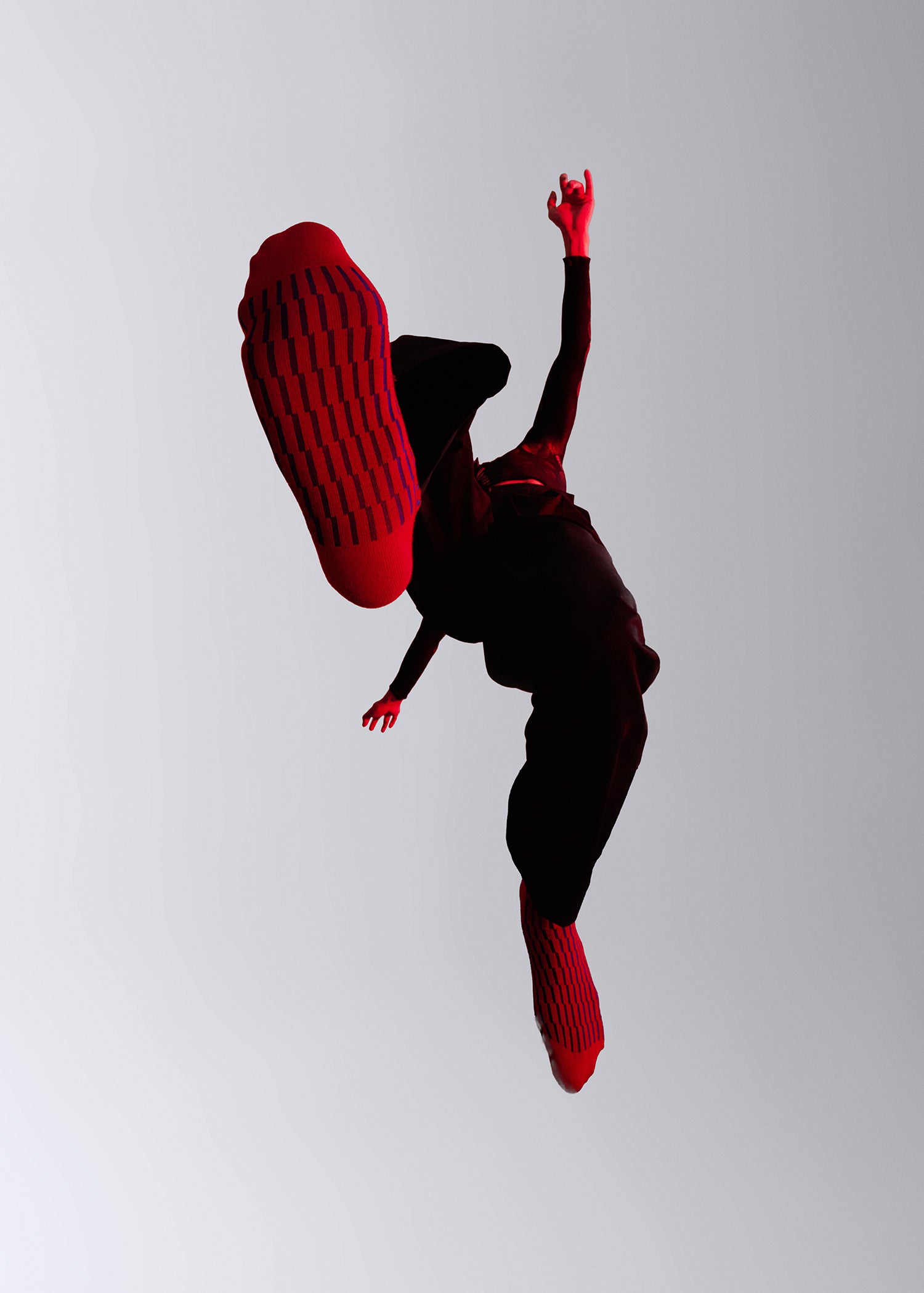 Silhouette of a person jumping while wearing the Shifting Grid Rib Socks in Red and Ultramarine
